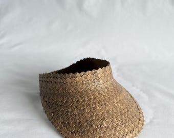 May include: A brown woven straw sun visor with a wide brim.