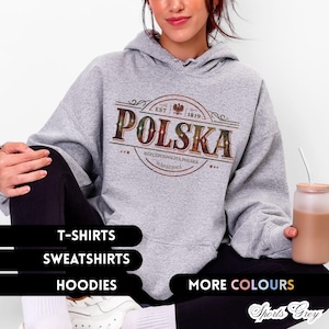 Könnte beinhalten: Ein hellgrauer Hoodie mit dem Wort "POLSKA" in einem kreisförmigen Design. Das Design enthält den Text "EST 1819", "RZECZPOSPOLITA POLSKA" und "WARSZAWA". Das Bild zeigt auch Text mit "T-SHIRTS", "SWEATSHIRTS", "HOODIES" und "MORE COLOURS".