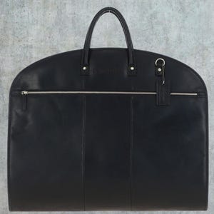 May include: Black leather garment bag with a zippered pocket and a small leather tag with the word "Travelpro" embossed on it.