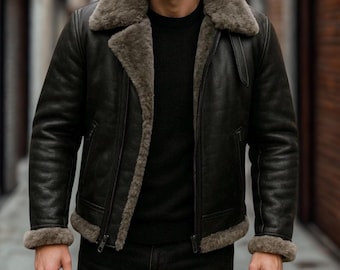 May include: A black leather jacket with a shearling collar and lining. The jacket has a zipper closure and a classic bomber style. The cuffs and hem are also lined with shearling. The jacket is worn over a black sweater.