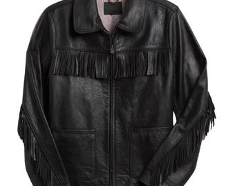 May include: Black leather jacket with fringe detailing across the chest and sleeves. The jacket features a collared neckline, a front zipper closure, and two front pockets. The interior lining is a light brown color.