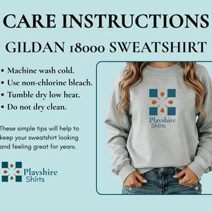 May include: A light gray crewneck sweatshirt featuring a blue and orange geometric logo with the text Playshire Shirts. The image includes care instructions for a Gildan 18000 sweatshirt, listing machine wash cold, non-chlorine bleach, and tumble dry low.