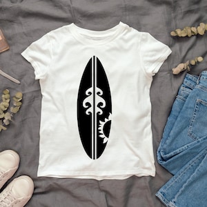 May include: White t-shirt with a black graphic of a surfboard with a wave and sun design.