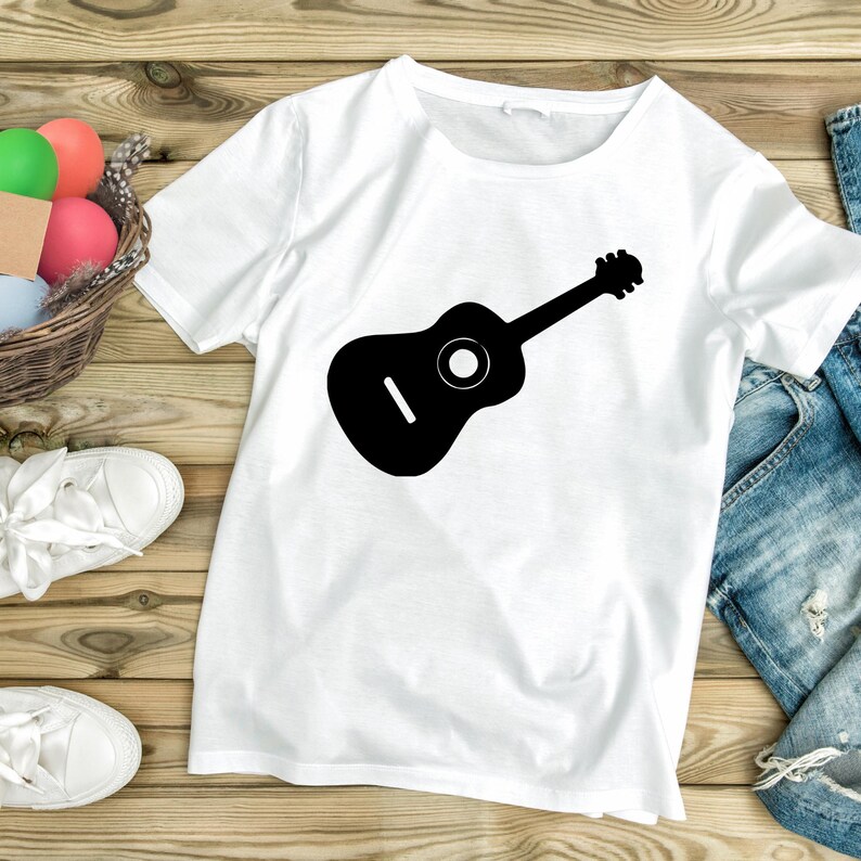 May include: White t-shirt with a black silhouette of an acoustic guitar printed on the front.