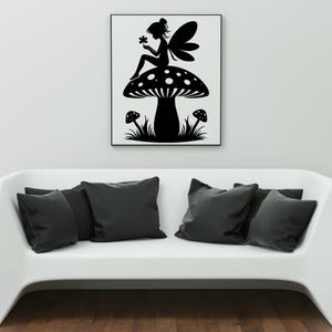 Op de afbeelding: Zwart-witte silhouet van een fee die op een paddenstoel zit met een bloem in haar hand. De fee heeft vleugels en een lange jurk. De paddenstoel heeft witte stippen en is omringd door gras.