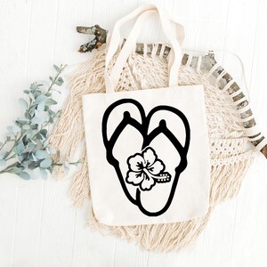May include: A white canvas tote bag with a black silhouette of flip flops and a hibiscus flower.