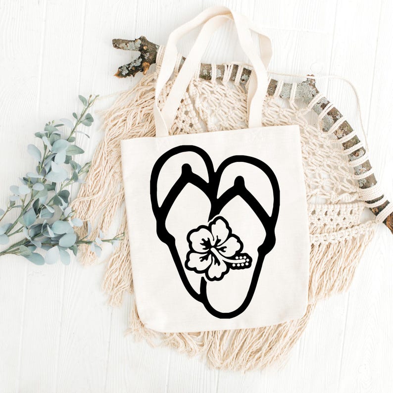 May include: A white canvas tote bag with a black silhouette of flip flops and a hibiscus flower.