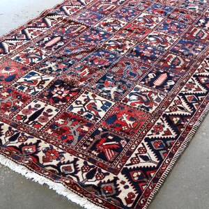 a large, colorful rug with intricate patterns and designs, placed on a concrete floor.