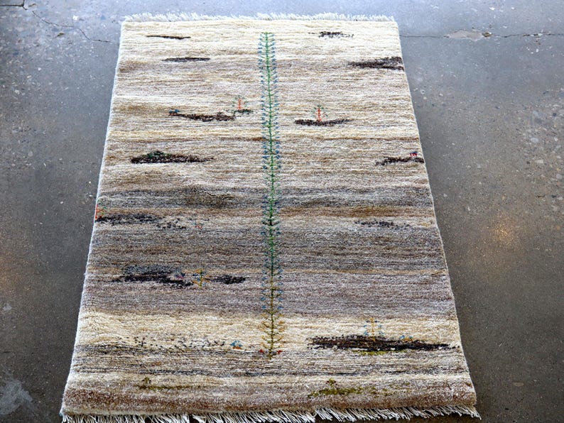 a rug with a geometric pattern and a vertical green line running through it, placed on a concrete floor.