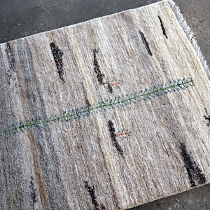 a rug with a geometric pattern of stripes and dots in various shades of gray and beige.