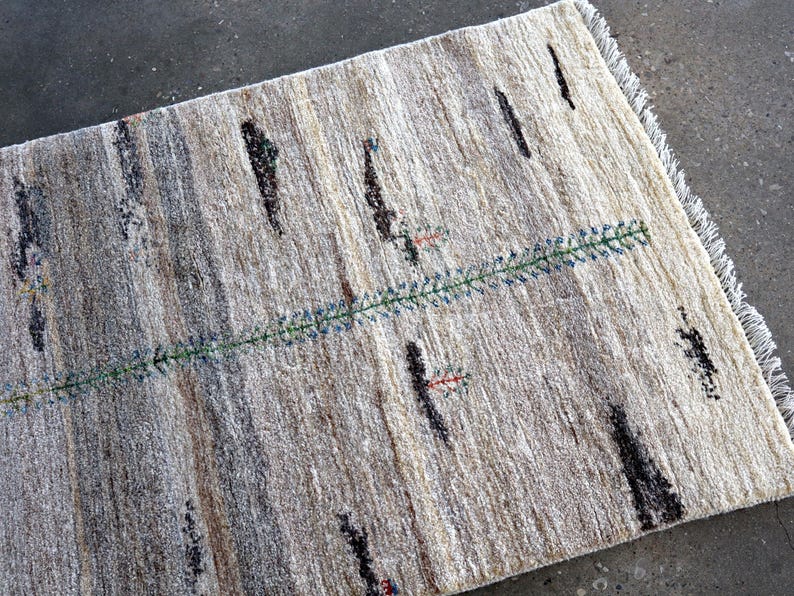 a rug with a geometric pattern of stripes and dots in various shades of gray and beige.