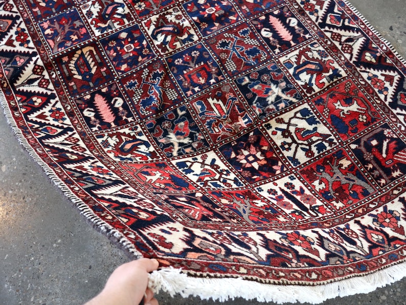 A hand is holding a colorful, intricately patterned rug with a variety of geometric shapes and designs.