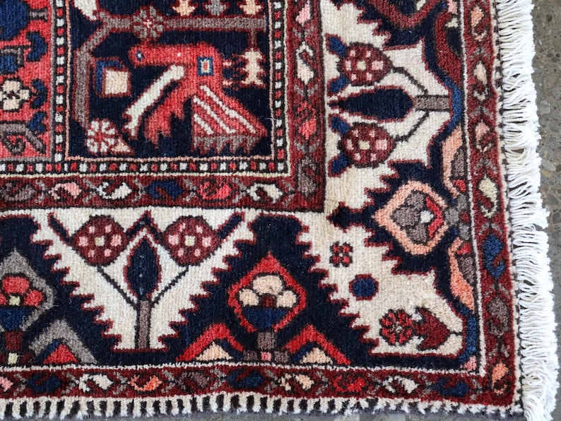 a close-up view of a colorful, intricately patterned rug with a mix of red, blue, and white colors. The rug features various geometric shapes and designs, including flowers, leaves, and geometric patterns. The rug appears to be a traditional rug, with a fringe at the edge.
