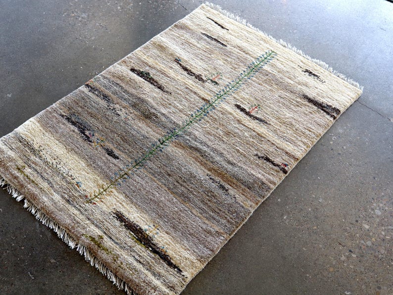a rug with a geometric pattern of stripes and a green line running through it, placed on a concrete floor.