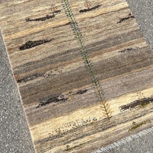 A pair of black sneakers stands on a rug with a geometric pattern, positioned on a gray pavement.