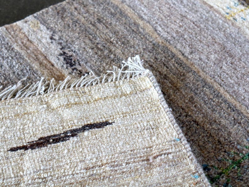 a close-up view of a textured fabric, possibly a rug or carpet, with a darker, more textured area in the background.