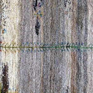 The image is a close-up of a textured surface with a pattern of vertical lines and small green and blue designs.