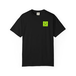 May include: Black t-shirt with a neon green square graphic on the upper left chest. The graphic features a skull design and the text "Glory Will Make Me God". The shirt has short sleeves and a crew neck.