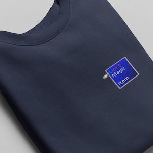 May include: A navy blue sweatshirt with a small blue square patch that says "Limit Magic Item" in a colorful, pixelated font.