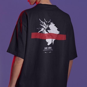 Könnte beinhalten: Schwarzes T-Shirt mit einer weißen und roten Grafik eines Charakters aus Final Fantasy VII. Das Design enthält den Text "CLOUD STRIFE" und weiteren Text darunter. Das T-Shirt hat kurze Ärmel und einen Rundhalsausschnitt.