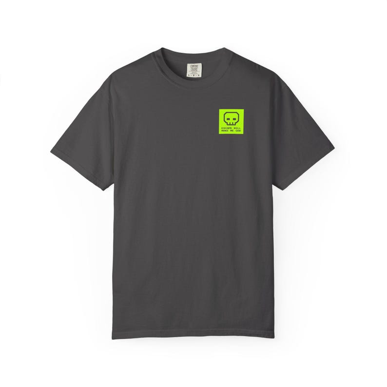 May include: Dark gray t-shirt with a neon green square graphic on the upper left chest. The graphic features a skull design and the text "SOCIETY WILL MAKE ME JAD". The shirt has short sleeves and a crew neck.