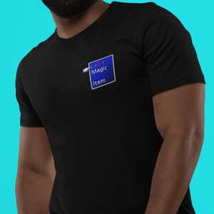 May include: Black t-shirt with a blue square graphic that reads "Limit Magic Item". The graphic has a white border and a gradient blue fill. The shirt is made of a soft material.
