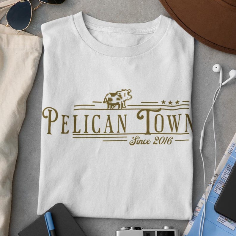 Stardew Valley Pelican Town T-Shirt in White, Ivory, and Moss colors