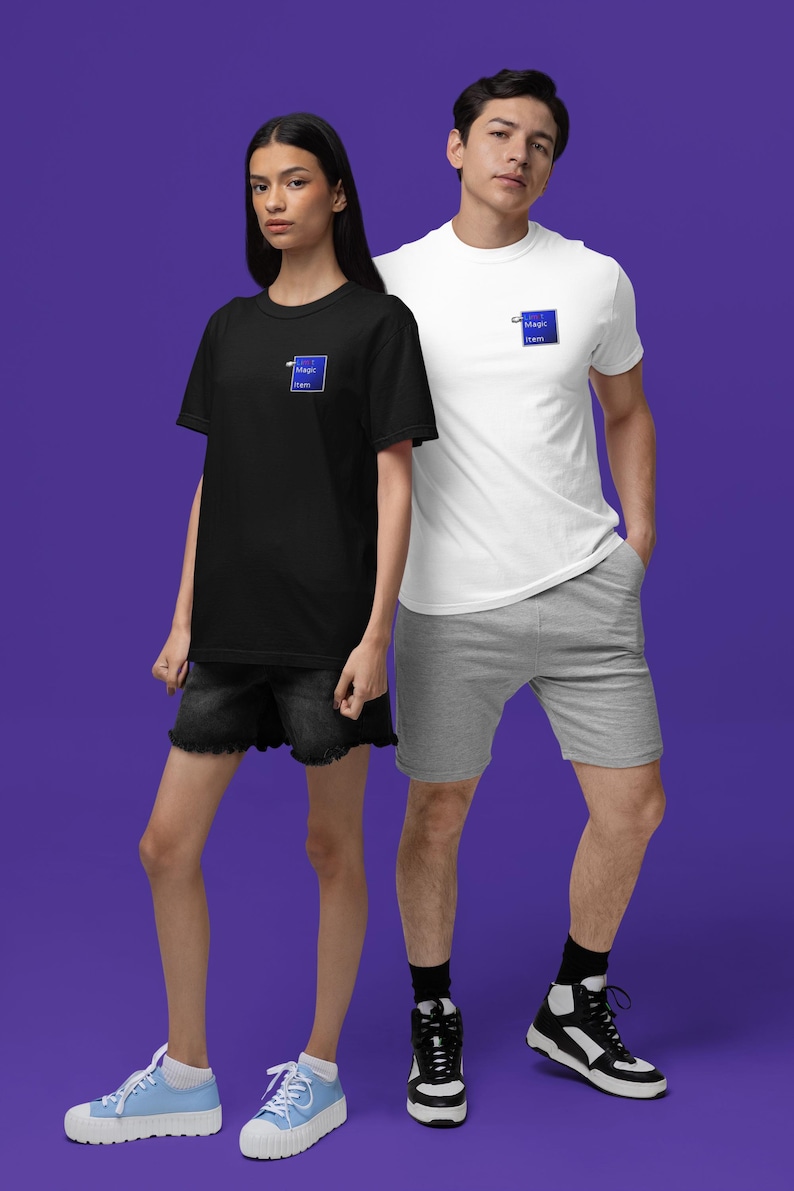 May include: A black t-shirt and a white t-shirt, each with a small blue square logo that reads "Magic Item". The models are wearing black denim shorts and gray shorts. The background is a solid purple.