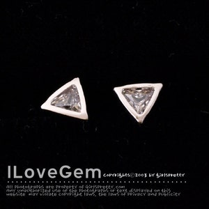Puede incluir: Un par de pendientes de plata de forma triangular con piedras de circonita cúbica transparentes.