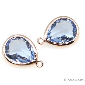 May include: Two light blue teardrop-shaped crystal charms with rose gold settings and jump rings.