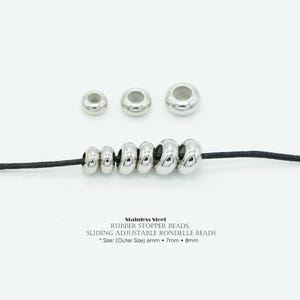 May include: Stainless steel sliding adjustable rondelle beads in various sizes, strung on a black cord. The beads are silver and have a smooth, rounded shape. The sizes are 6mm, 7mm, and 8mm.
