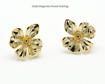 Könnte beinhalten: Zwei goldfarbene Ohrringe in Form von Magnolienblüten. Die Ohrringe haben strukturierte Blütenblätter und einen zentralen Cluster aus kleinen, runden Akzenten. Der Text "Gold Magnolia Flower Earrings" steht darüber.
