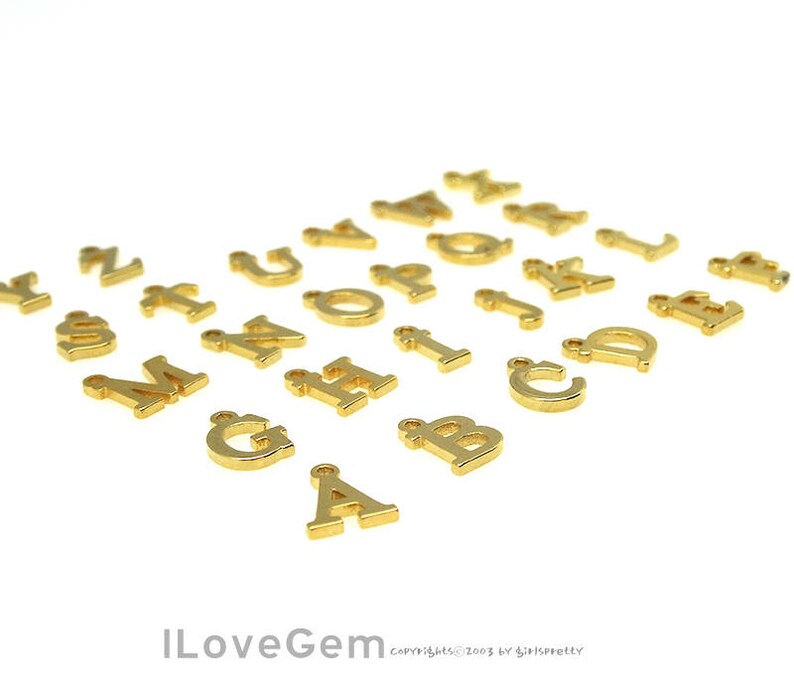 May include: Gold-colored metal alphabet letter charms. Each letter is separate and has a hole for attaching to a necklace, bracelet, or other jewelry.