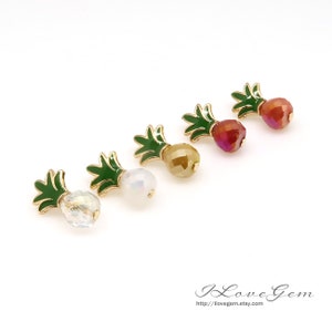 May include: Five pairs of gold pineapple earrings with different colored crystal stones. The stones are white, gold, red, and pink.
