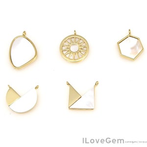 May include: Six gold-toned metal pendants with white mother-of-pearl inlays. The pendants are in various shapes, including a circle, a hexagon, a crescent moon, a teardrop, and two geometric shapes.