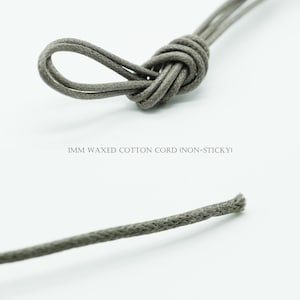 May include: Close-up of gray 1mm waxed cotton cord, knotted and unknotted. The text "1MM WAXED COTTON CORD (NON-STICKY)" is visible. The cord appears to be a muted, neutral color.