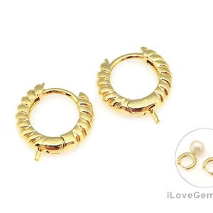 May include: A pair of gold hoop earrings with a textured design. The earrings are shown with a pair of pearl earrings.