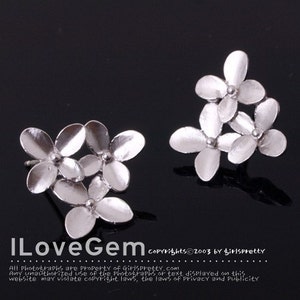 May include: A pair of silver flower-shaped earrings. Each earring features three delicate flowers clustered together.