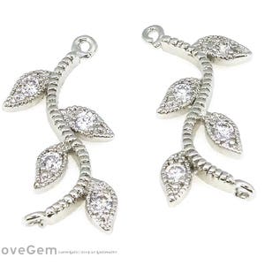 May include: Two silver-toned leaf-shaped charms with clear crystal accents. Each charm has a loop at the top for attaching to jewelry.