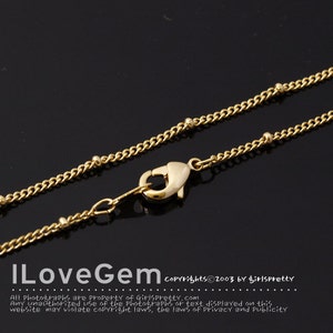 Pode incluir: Um colar de corrente de ouro com fecho de lagosta. A corrente tem pequenas contas redondas espaçadas ao longo da corrente.