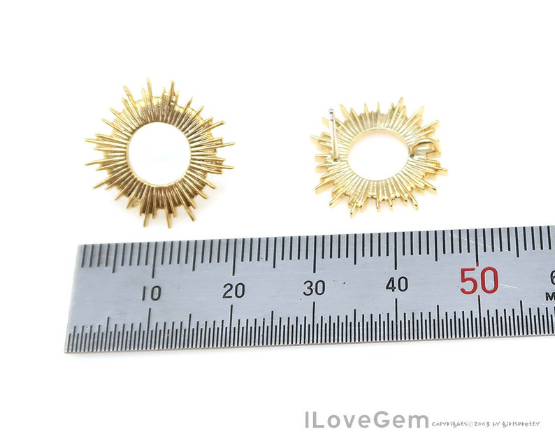 K&ouml;nnte beinhalten: Zwei goldfarbene Sonnenstrahlen-Ohrringe mit einem runden Design. Die Ohrringe werden mit einem Lineal gemessen und zeigen, dass sie einen Durchmesser von etwa 5 cm haben.