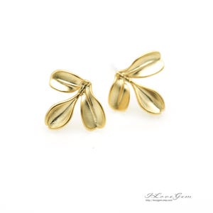May include: A pair of gold-toned earrings shaped like three small leaves.