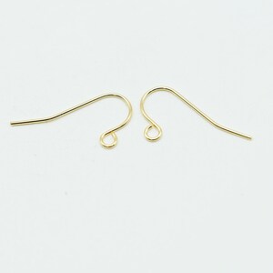 May include: Two gold-toned metal earring hooks, each featuring a curved wire design with a small circular loop at the bottom for attaching jewelry components. These findings are smooth, polished, and have a consistent metallic yellow finish.