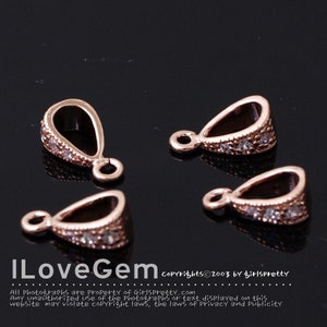 May include: Four rose gold pendant bails with clear rhinestone accents. The bails are teardrop shaped with a loop at the top.