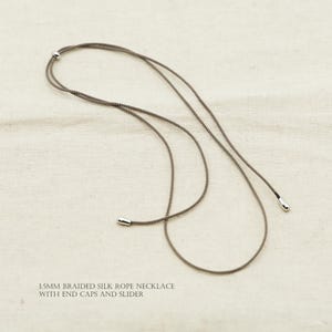 Puede incluir: Una taza de cerámica blanca con un asa negra y el texto "But First, Coffee" en negro, con una fuente de estilo manuscrito. La taza está sobre una superficie blanca.