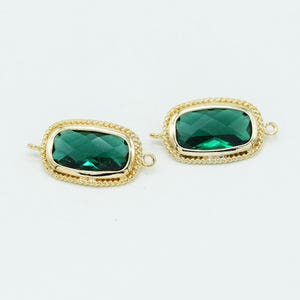May include: Two rectangular jewelry connectors featuring faceted emerald green stones set in gold-toned metal frames. Each piece has a twisted rope-style border and two small loops on opposite sides for attachment to chains or other jewelry components.