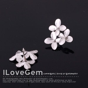 May include: A pair of silver earrings with a flower design. Each earring features three small flowers clustered together.