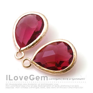 May include: Two teardrop-shaped red glass beads with gold-toned metal settings and loops. The beads are approximately 1 inch in length.
