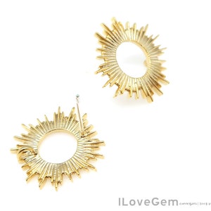 K&ouml;nnte beinhalten: Ein Paar goldene Sonnenstrahlen-Ohrringe mit einem runden Design. Die Ohrringe haben einen Stiftverschluss.