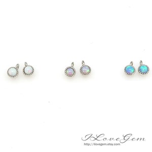May include: Six small round opal charms with silver settings. The charms are in three colors: white, light purple, and light blue.